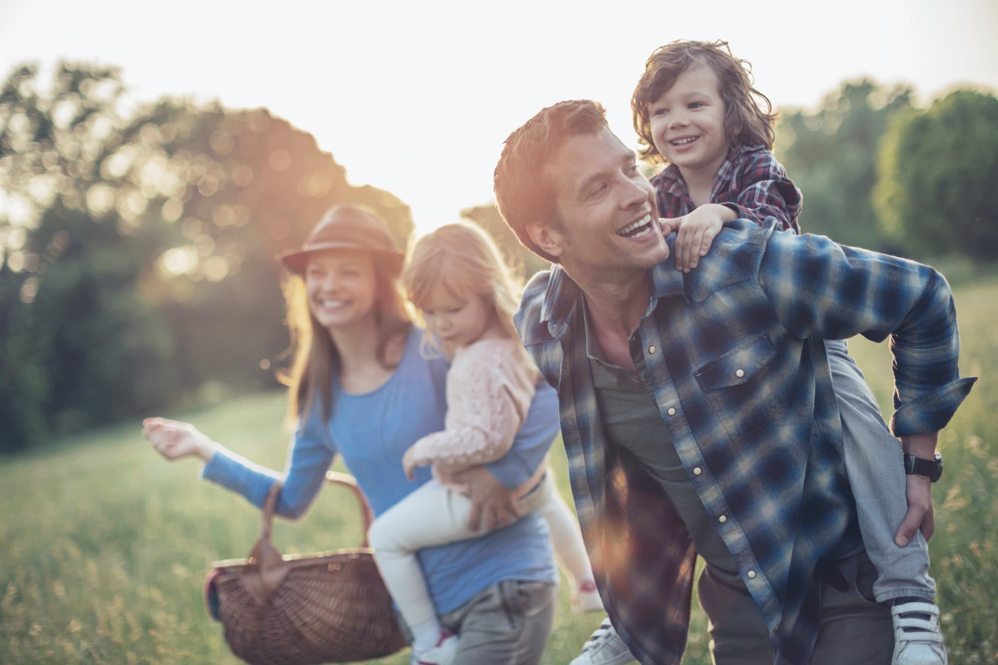 Familie mit zwei Kindern bei einem Spaziergang über eine sommerliche Wiese